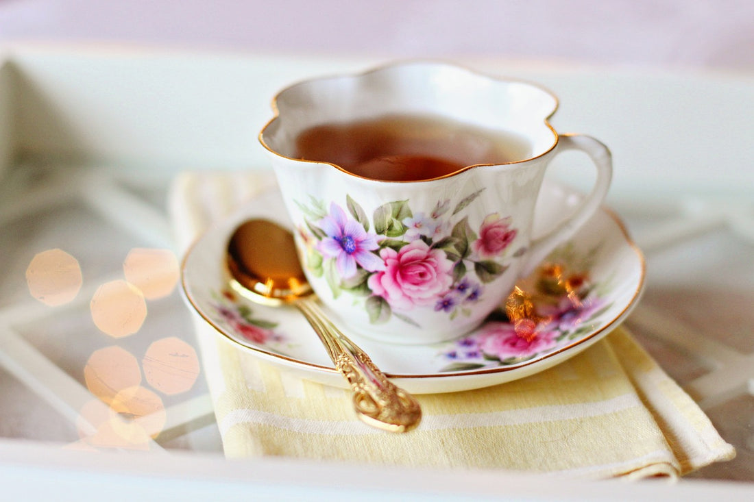 Cup of English Breakfast Tea in a cup and saucer with flower prints and gold spoon